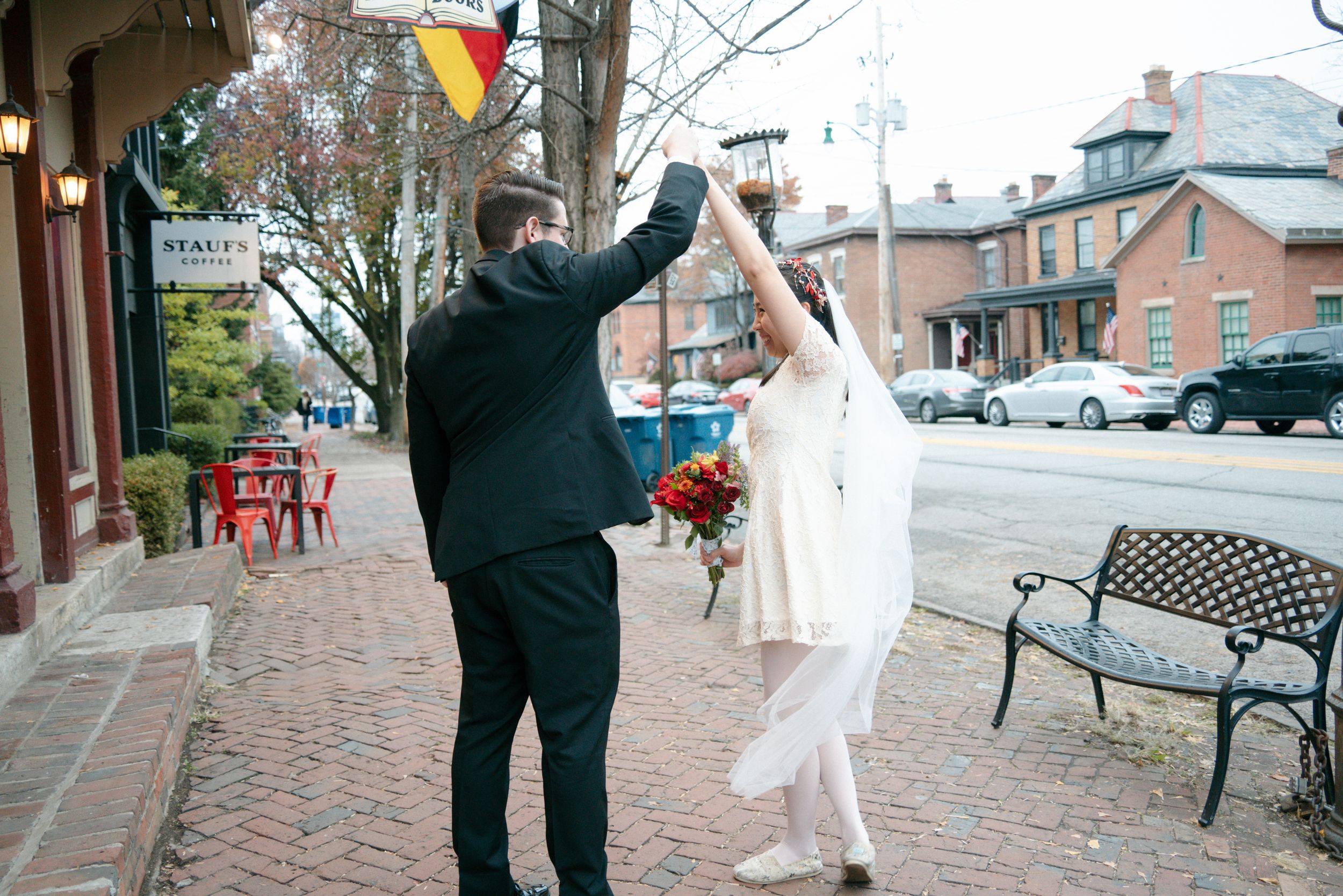 Bride and groom spin on a brick sidewalk outside a shop in a charming small town street.