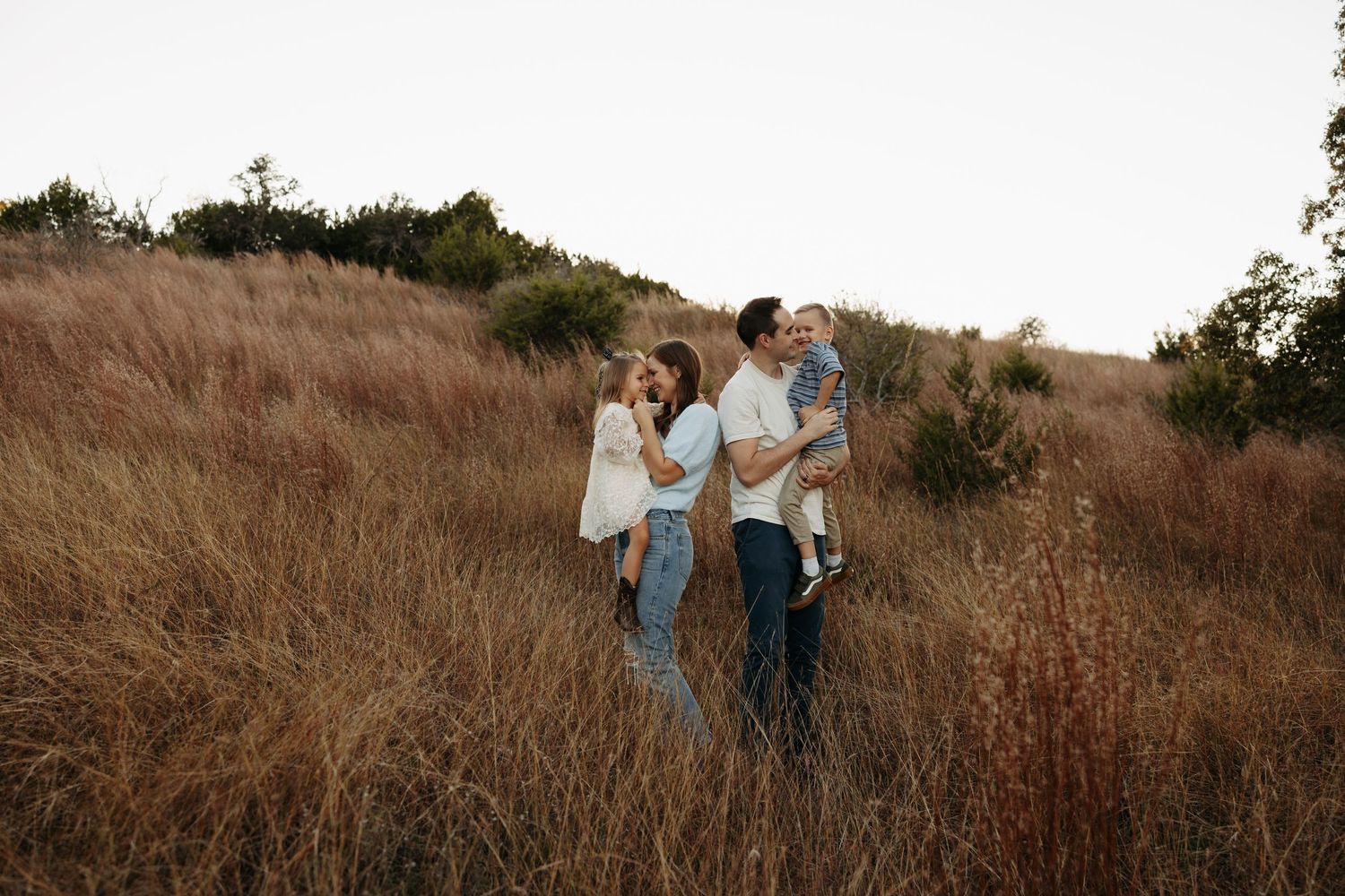 Couple walking hand in hand on dirt path through sunny meadow.