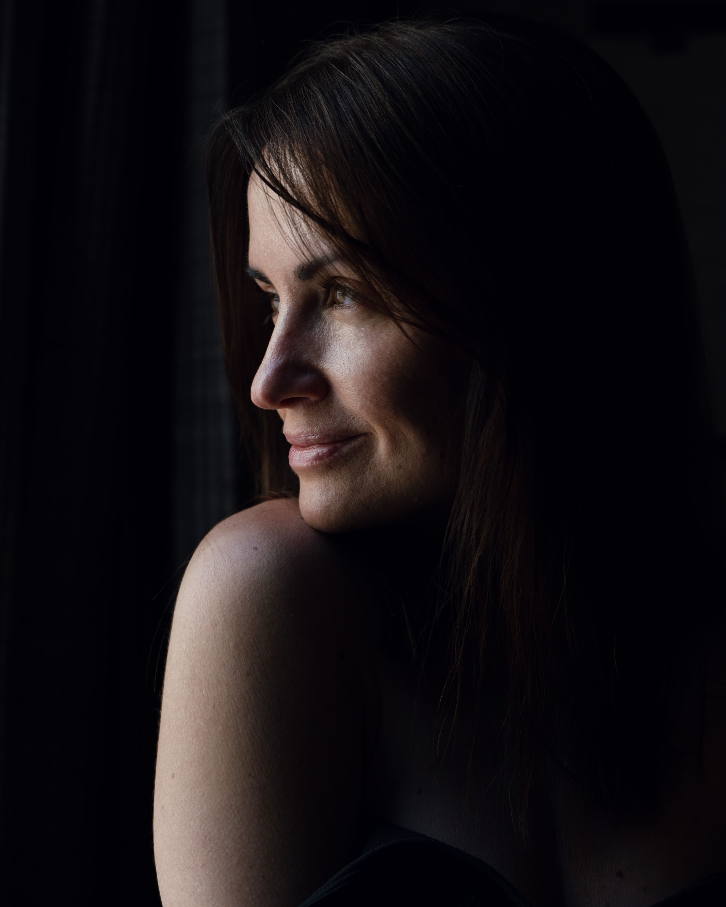 Artistic portrait of a woman in profile, reflected in a dark surface.
