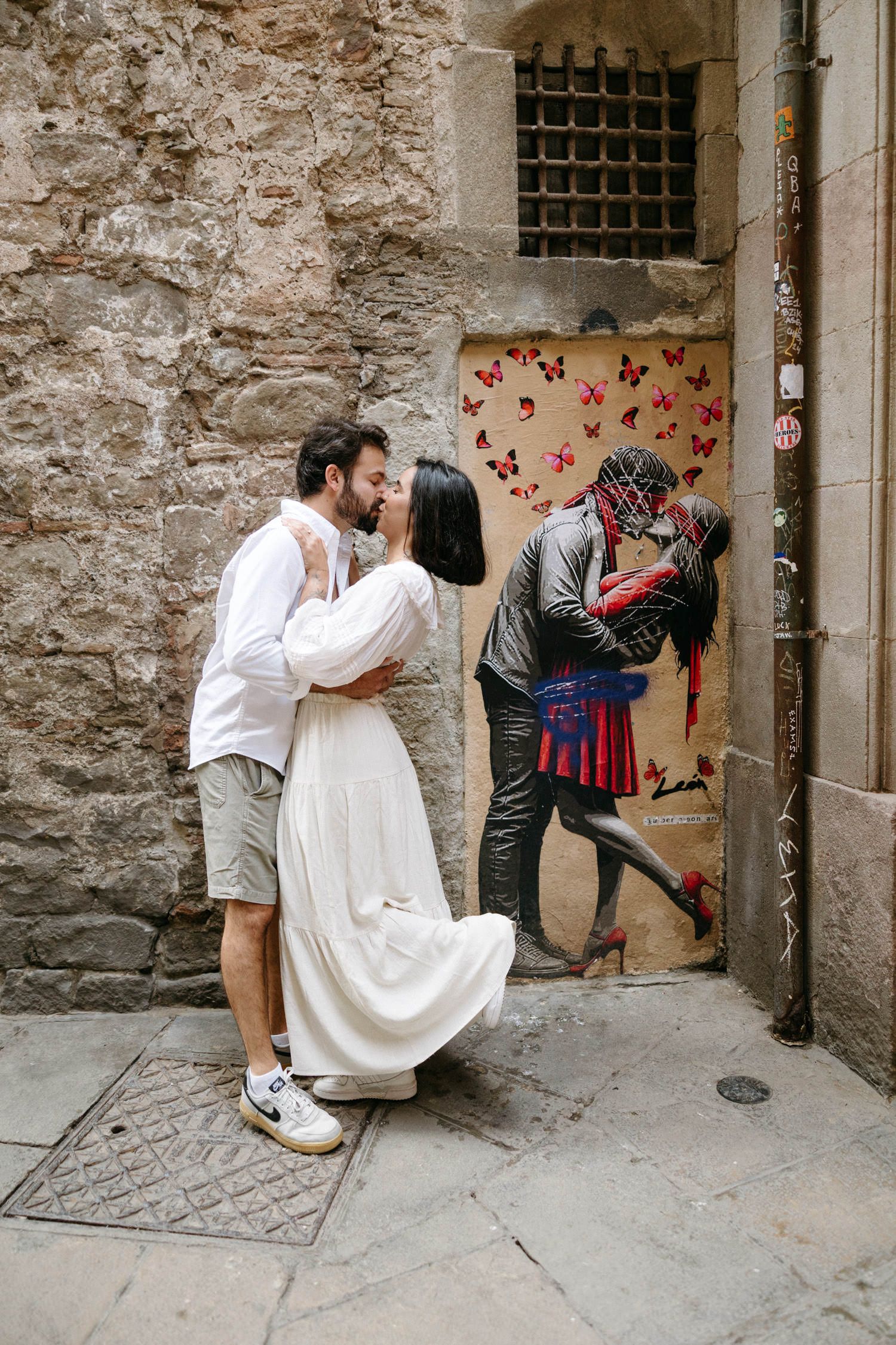 A romantic photoshoot of a couple against rustic stone walls in an old city quarter.