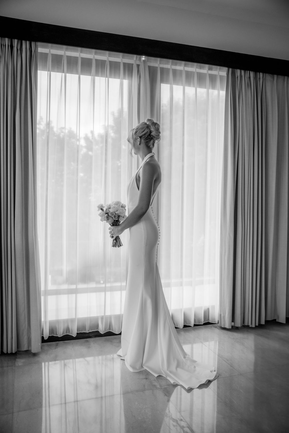 Black and white triptych photograph of a bride in a white wedding dress standing by sunlit windows.