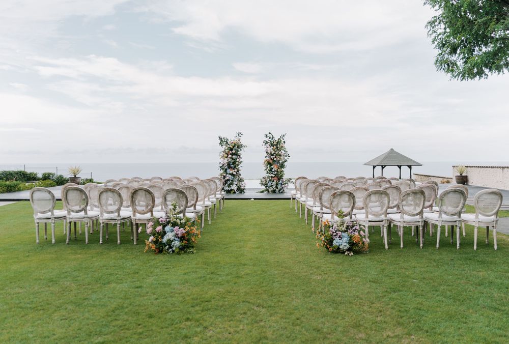 Outdoor wedding ceremony setup with white chairs arranged in rows overlooking a scenic mountain landscape.