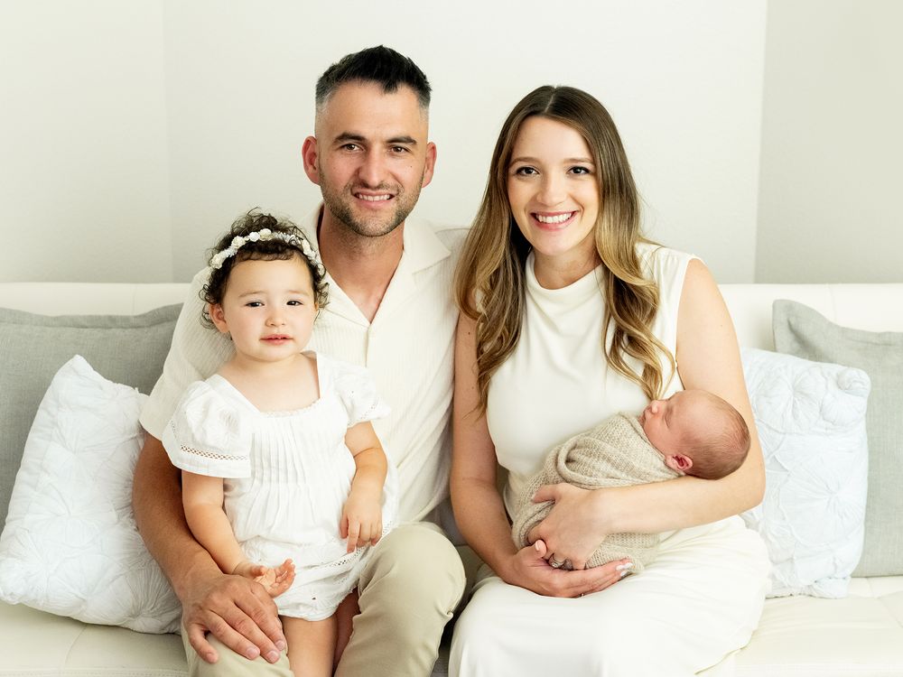 A collection of intimate family photos on a white bedspread showing tender moments between loved ones at home.