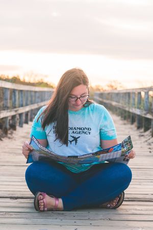 woman travel agent sits on a boardwalk with a map in hand