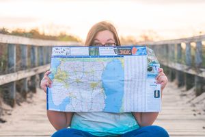 travel agent poses playfully behind map