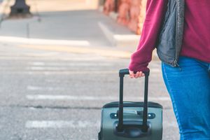 woman walks across walkway with suitcase