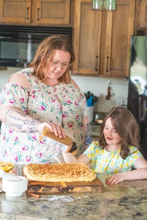 Mother and daughter bake cinnamon rolls in a kitchen