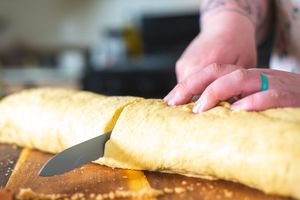 baker slices cinnamon rolls