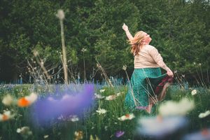 bohemian, earthy woman dances in field of flowers