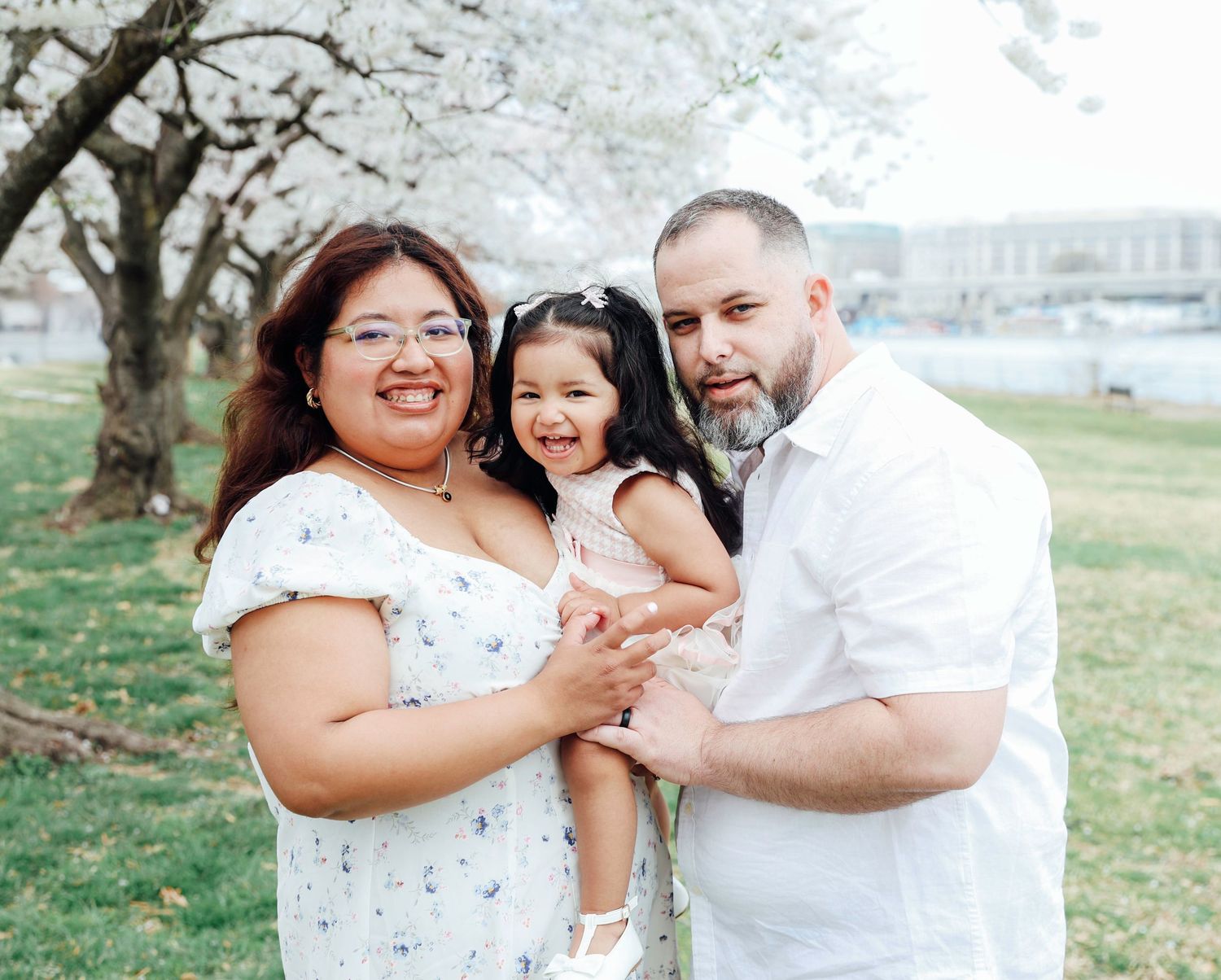 A loving family enjoys a joyful outdoor portrait session together in a dreamy meadow setting at sunset.
