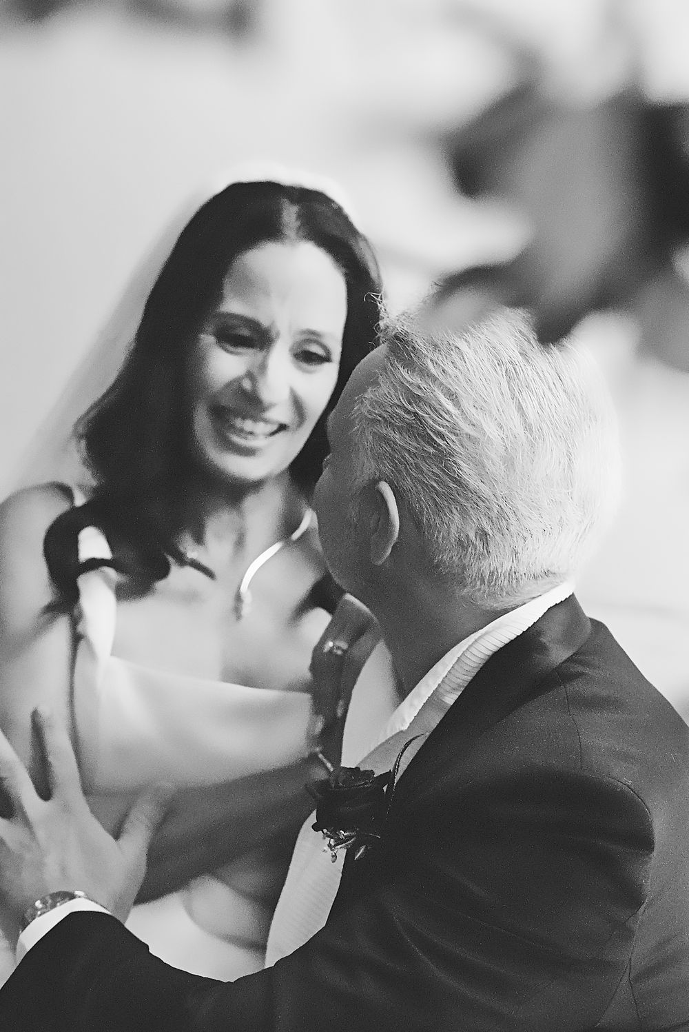 Black and white candid photo showing two people having a joyful conversation at a formal event.