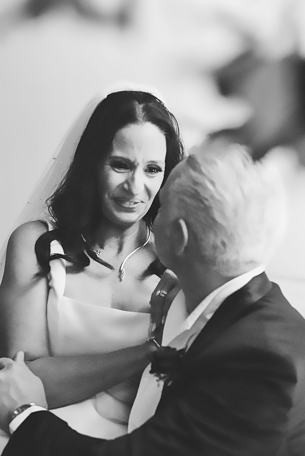 A couple dances together in an elegant embrace during what appears to be a special celebration captured in black and white.
