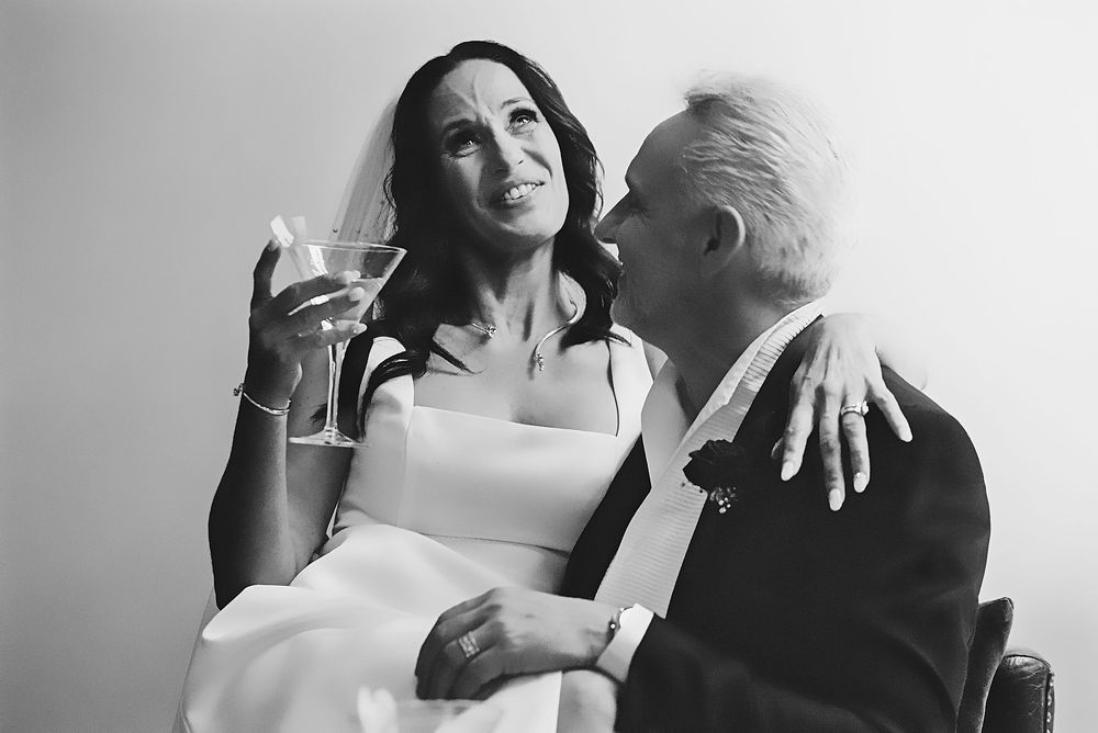 Black and white photo series showing couple toasting and laughing together during romantic moment.