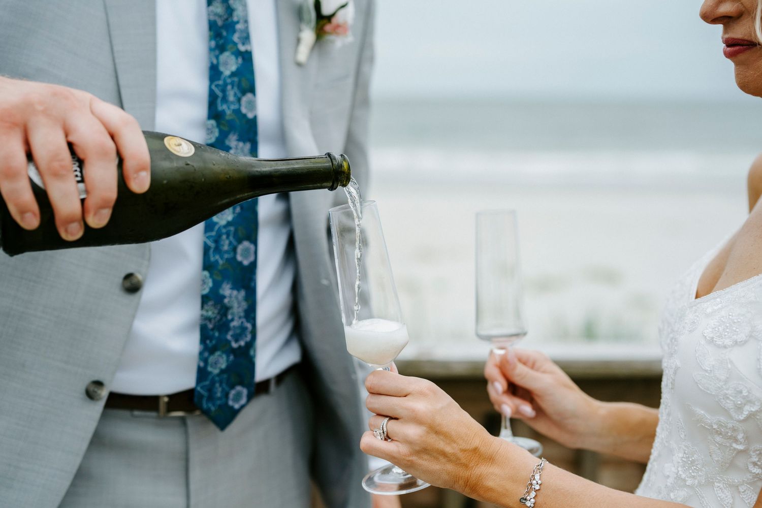 Hands pour champagne into elegant glasses during a formal celebration event.