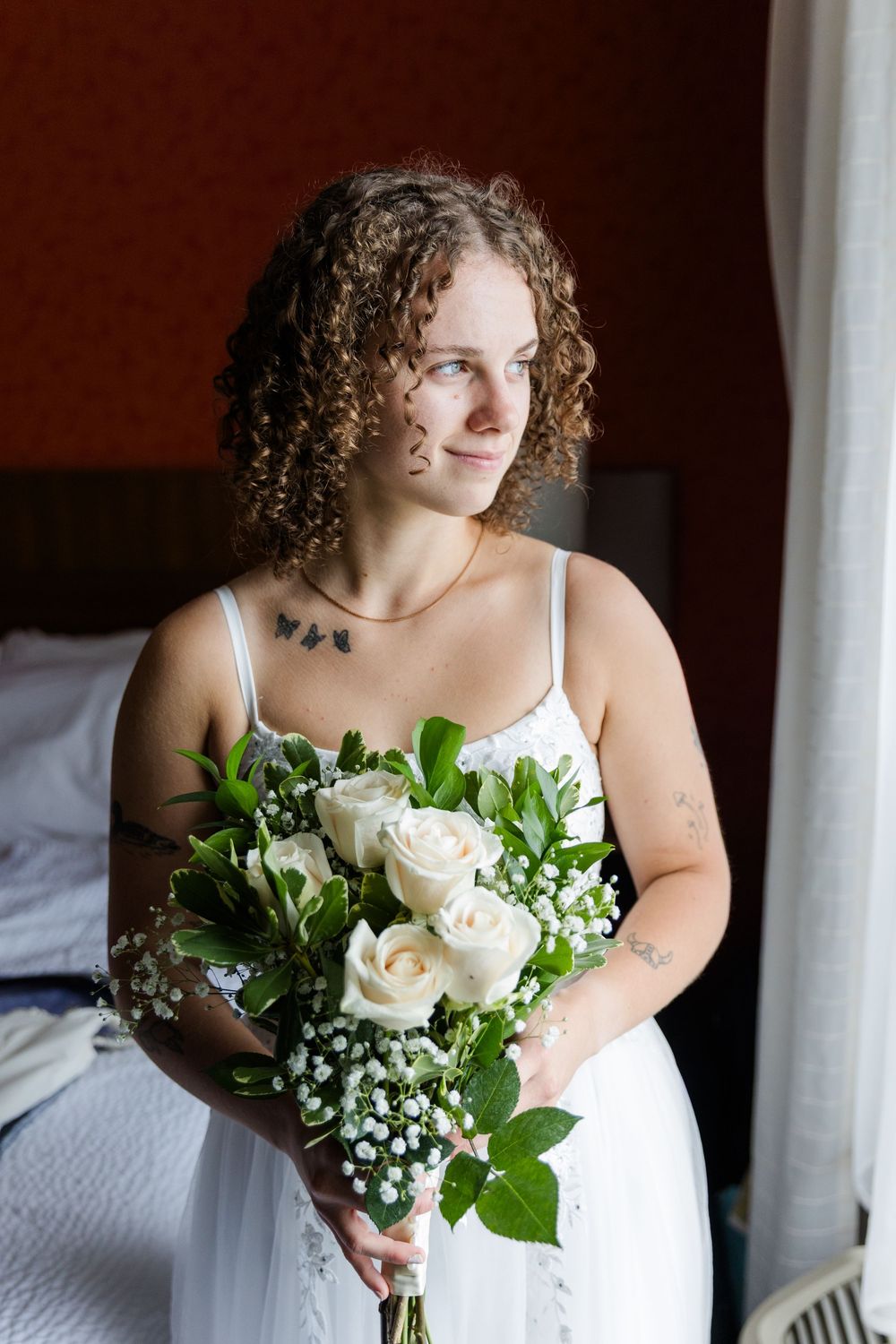 Classic white bridal bouquet featuring roses and baby's breath held against a white dress.