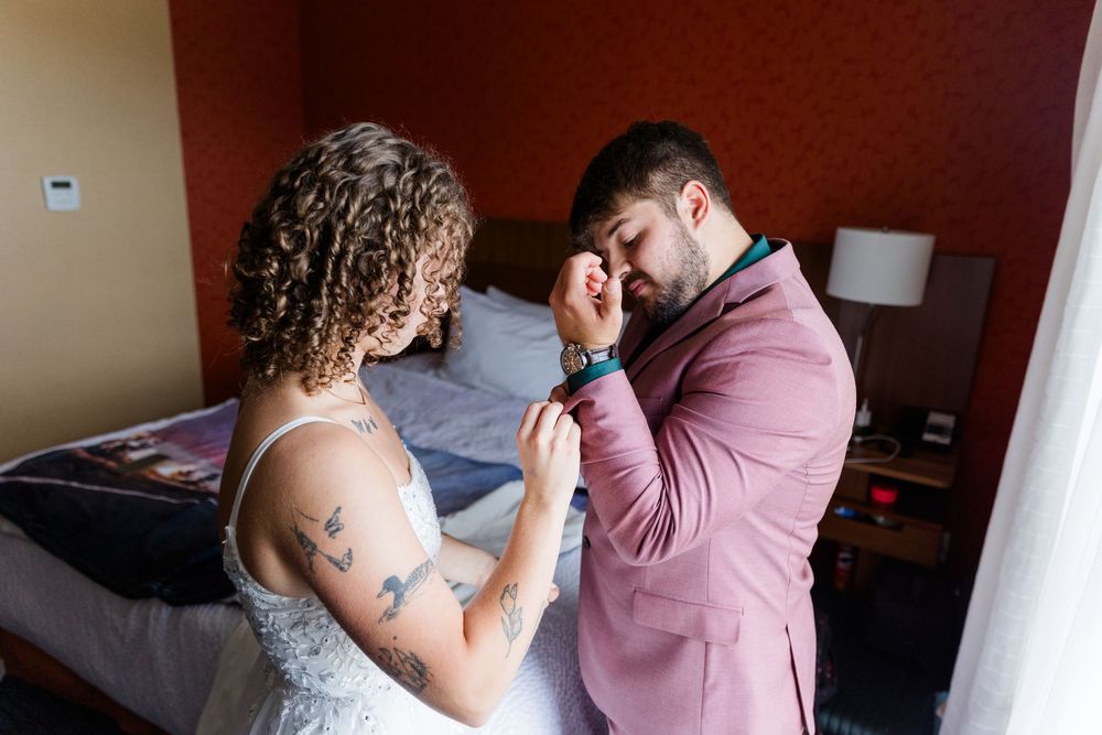Intimate moment captured as couple prepares for wedding ceremony in hotel bedroom.