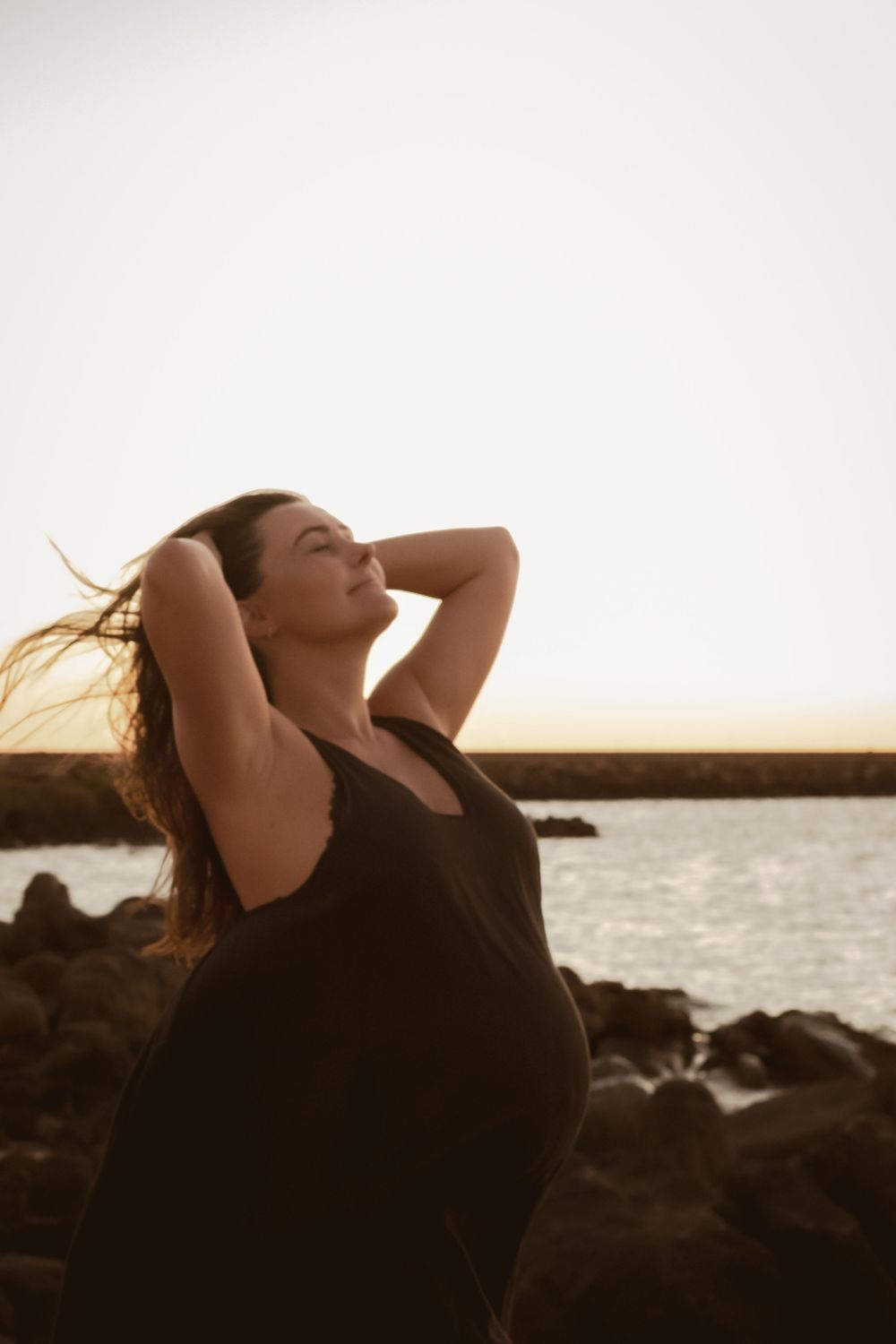 A silhouette against a sunset sky over rocky coastline during golden hour.