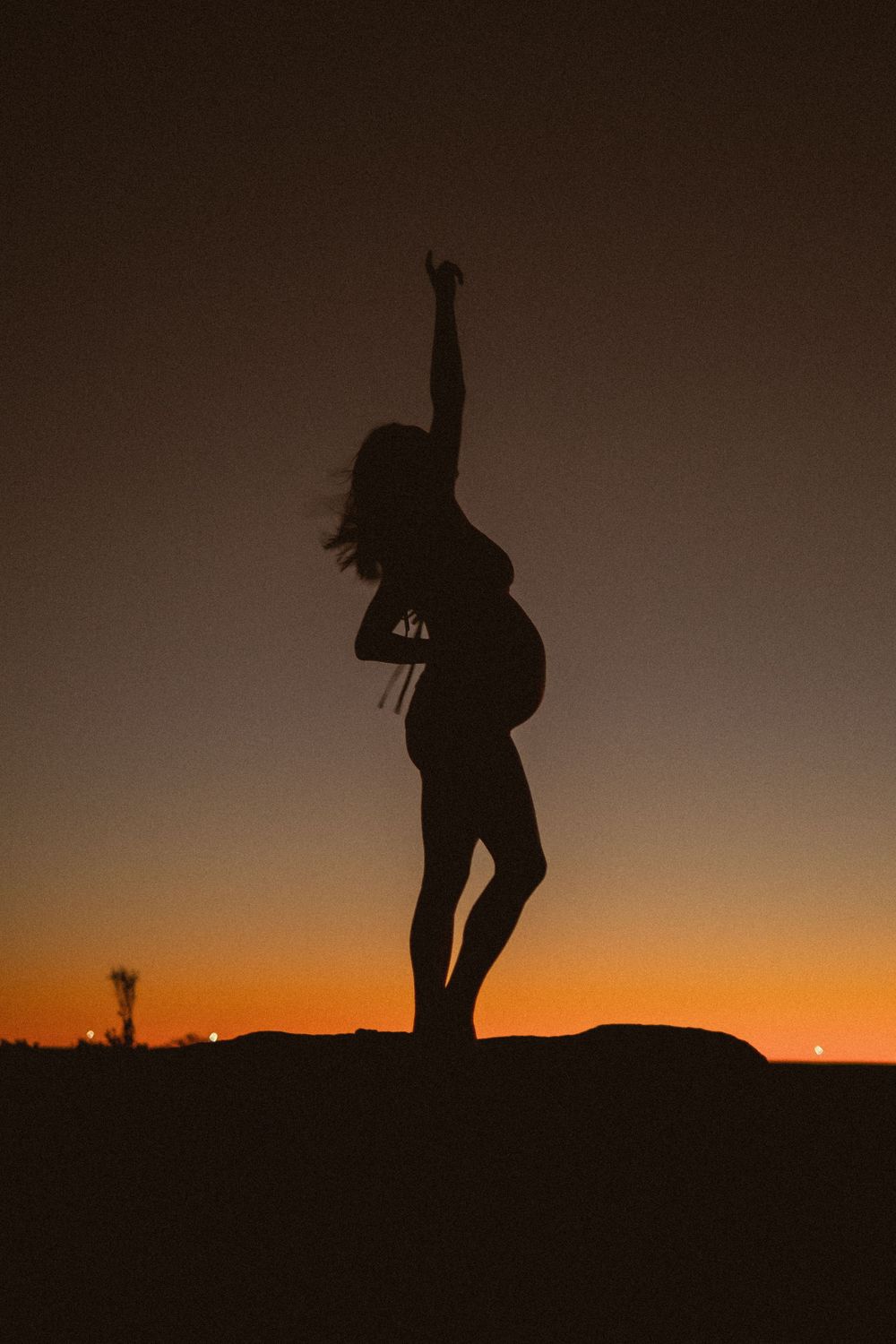Artistic silhouette of dancing figure against vibrant orange sunset sky.