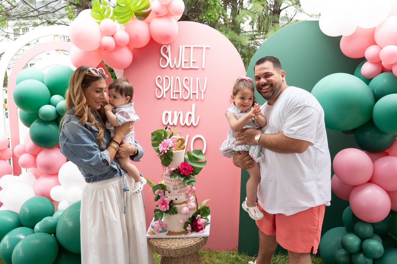 Outdoor party setup with pink and green balloon decorations and celebratory signage.
