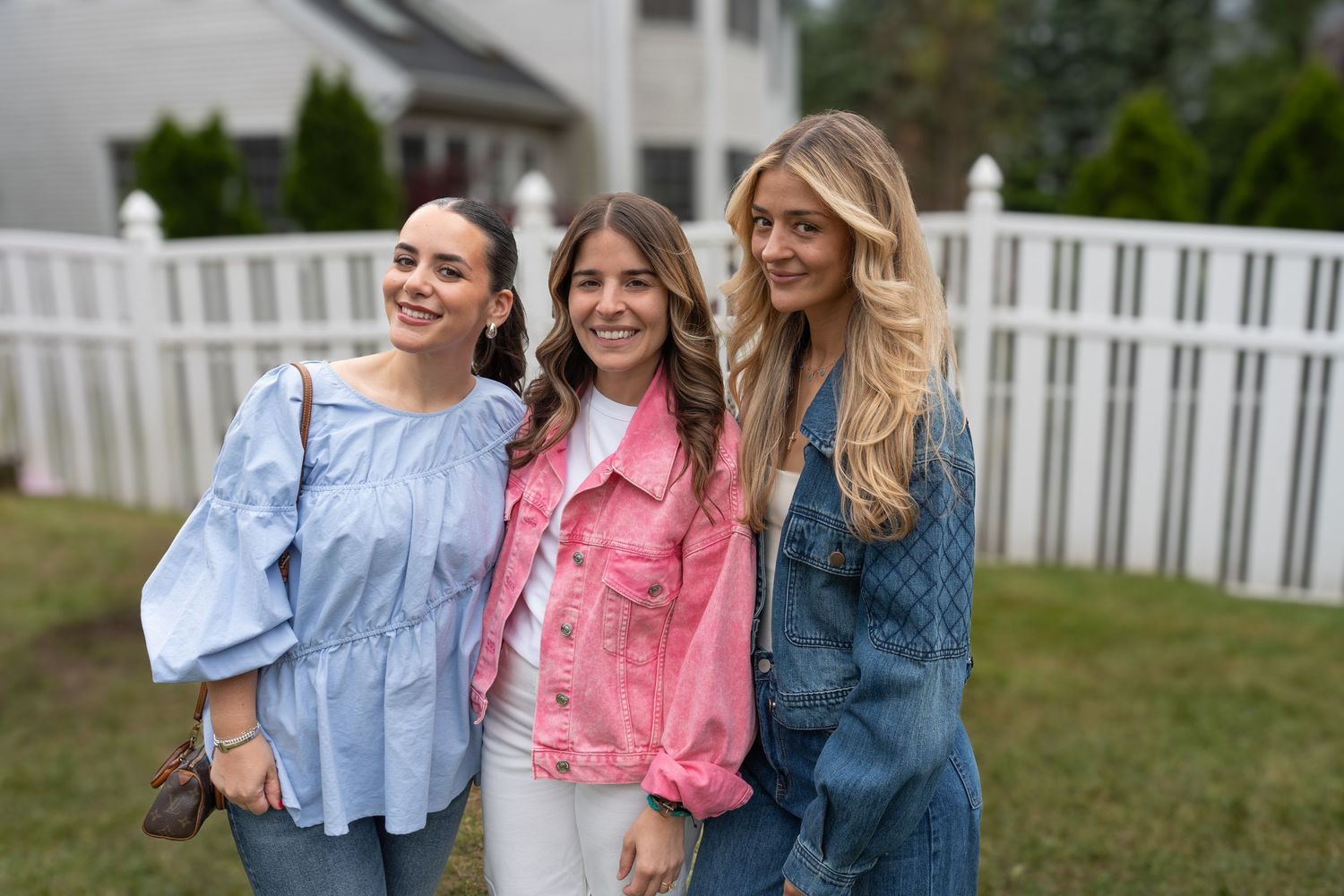 Guests in coordinated pastel outfits posing together at an outdoor celebration.
