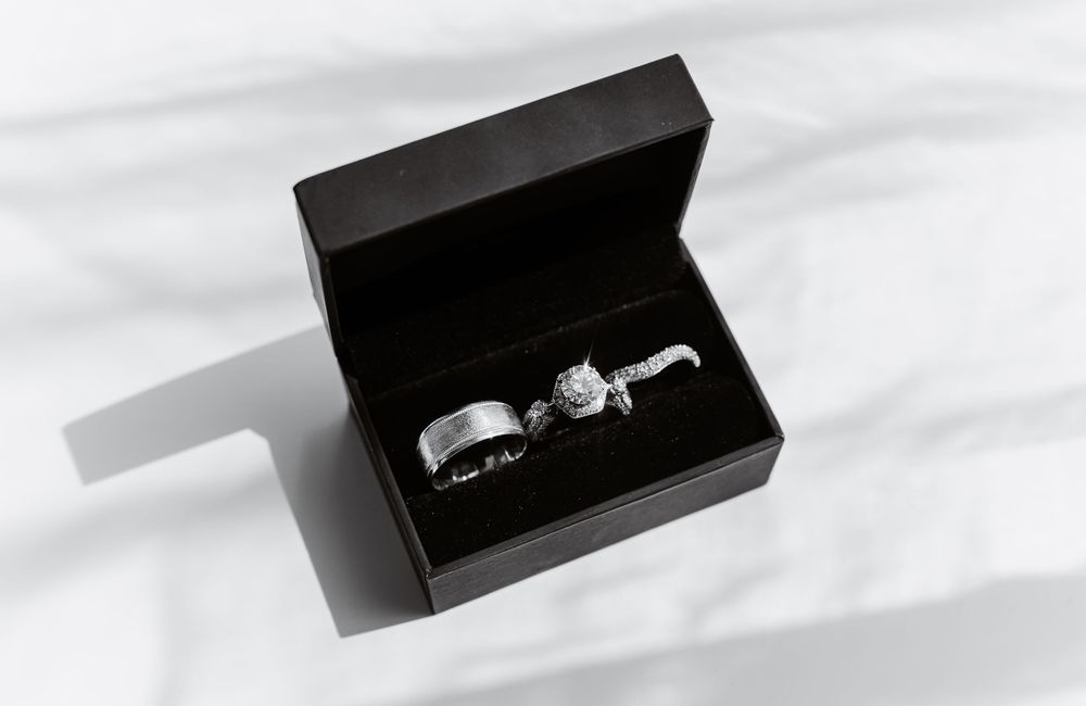 Two wedding rings displayed in a black jewelry box against white fabric.