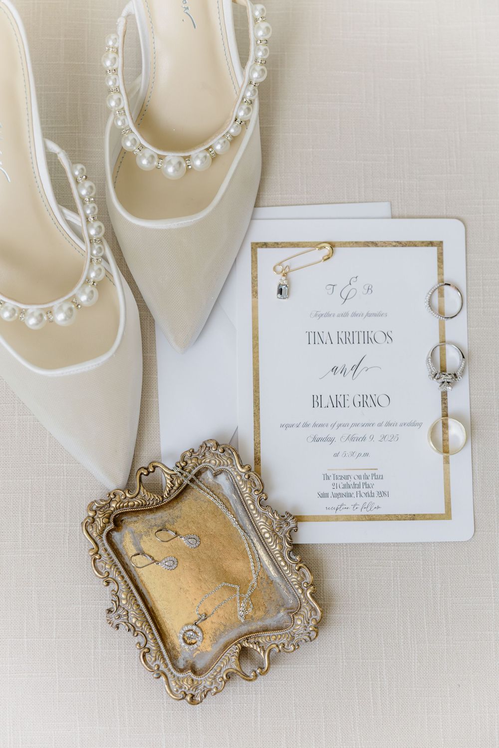 Wedding invitation and bridal shoes displayed with vintage gold tray and wedding rings.