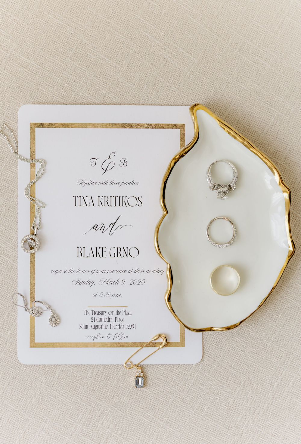Elegant wedding invitation with gold trim and wedding rings arranged on neutral background.