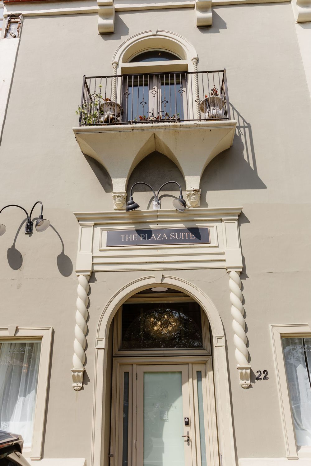 Mediterranean-style building exterior with cream walls, arched doorways and decorative balconies.