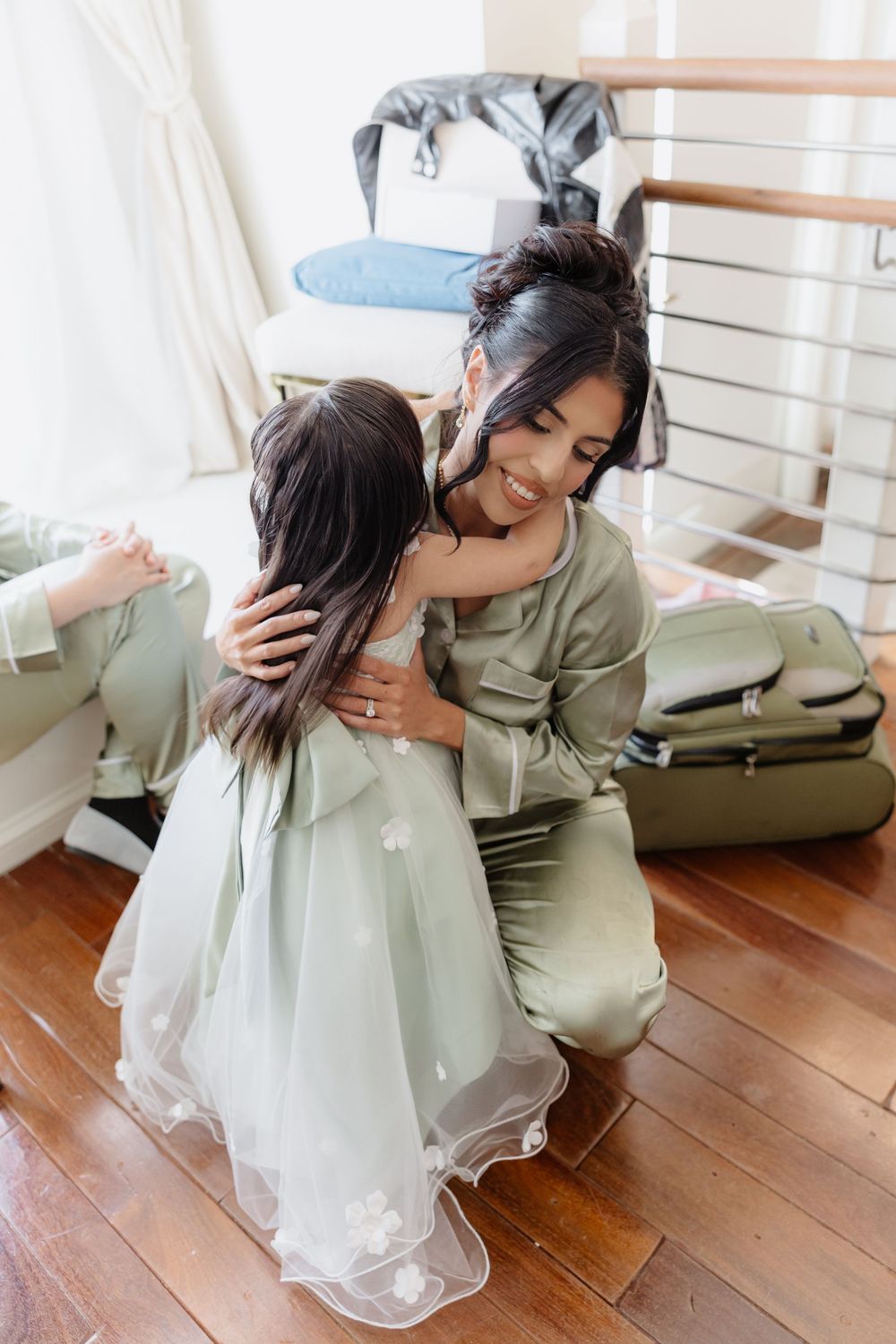 A tender moment captured between two people in sage green attire on hardwood floors.