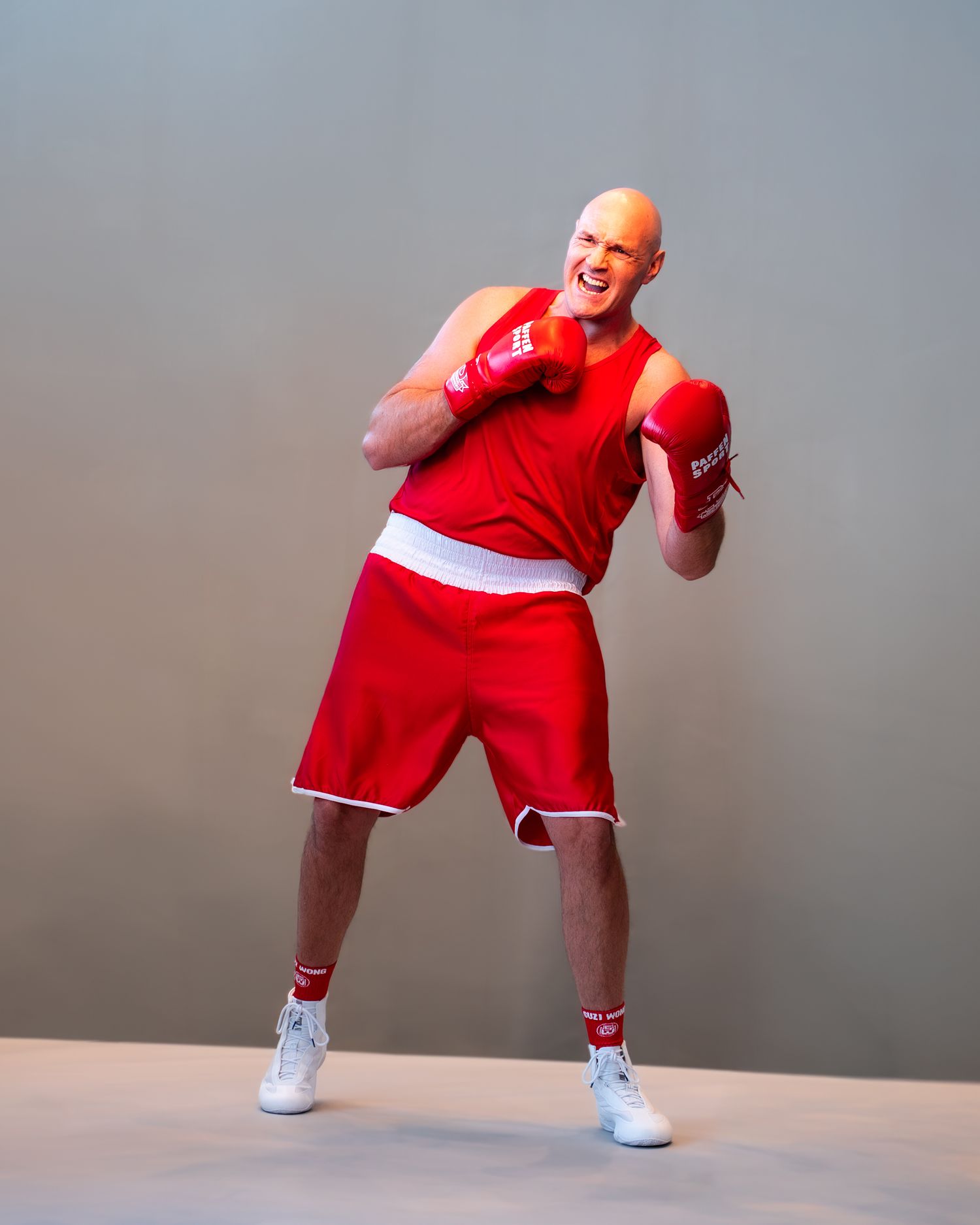 Person in red athletic wear performs dynamic dance moves against a gray studio backdrop.