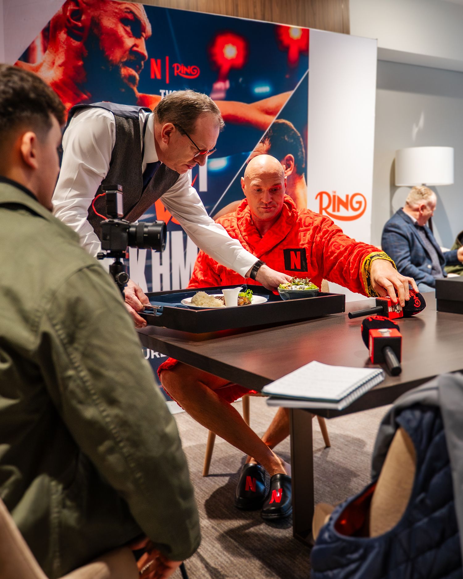 People gathered around a table during a business meeting with red lighting and decor in the background.