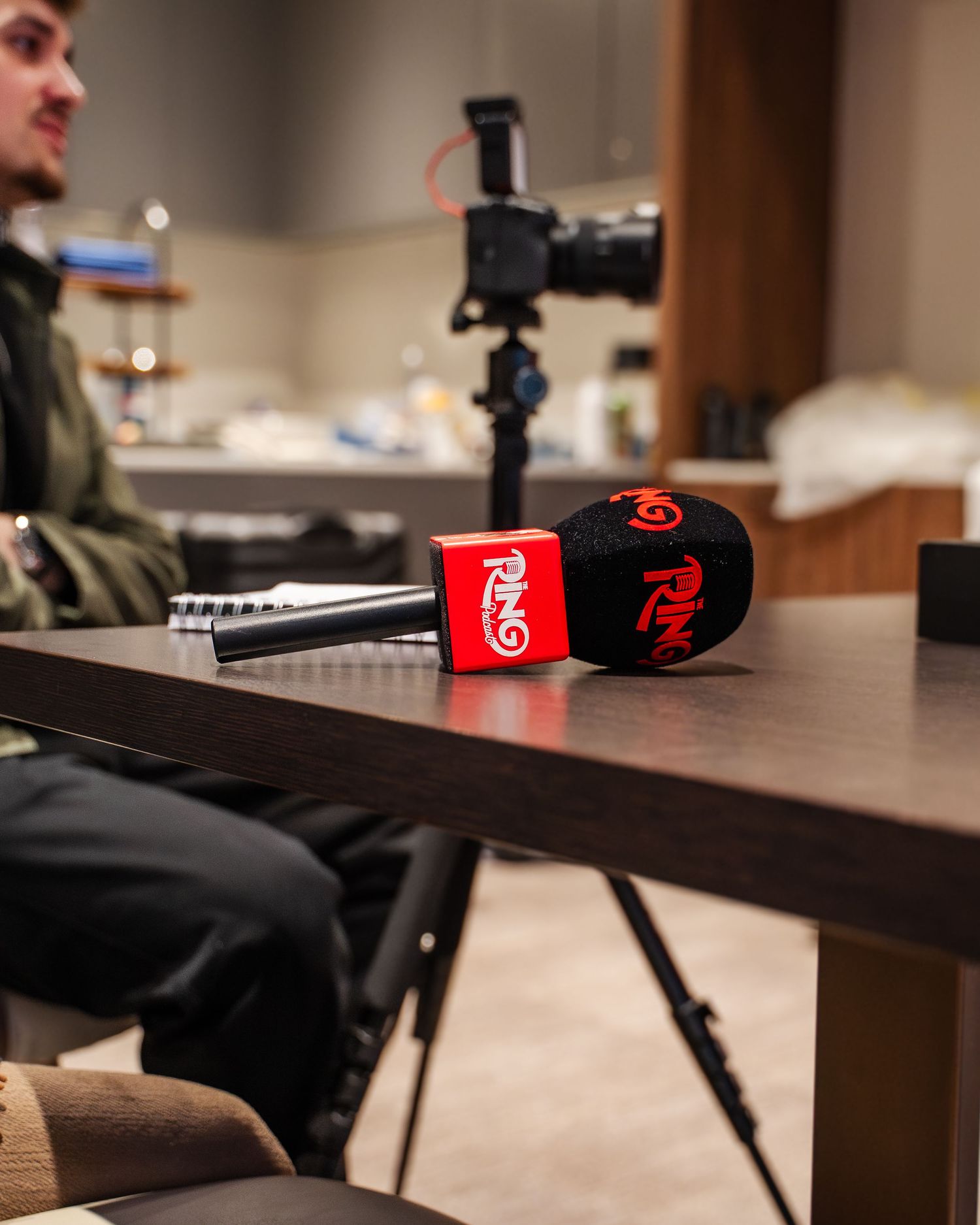 Professional recording equipment including microphones and headphones arranged on a dark wooden desk in a studio setting.