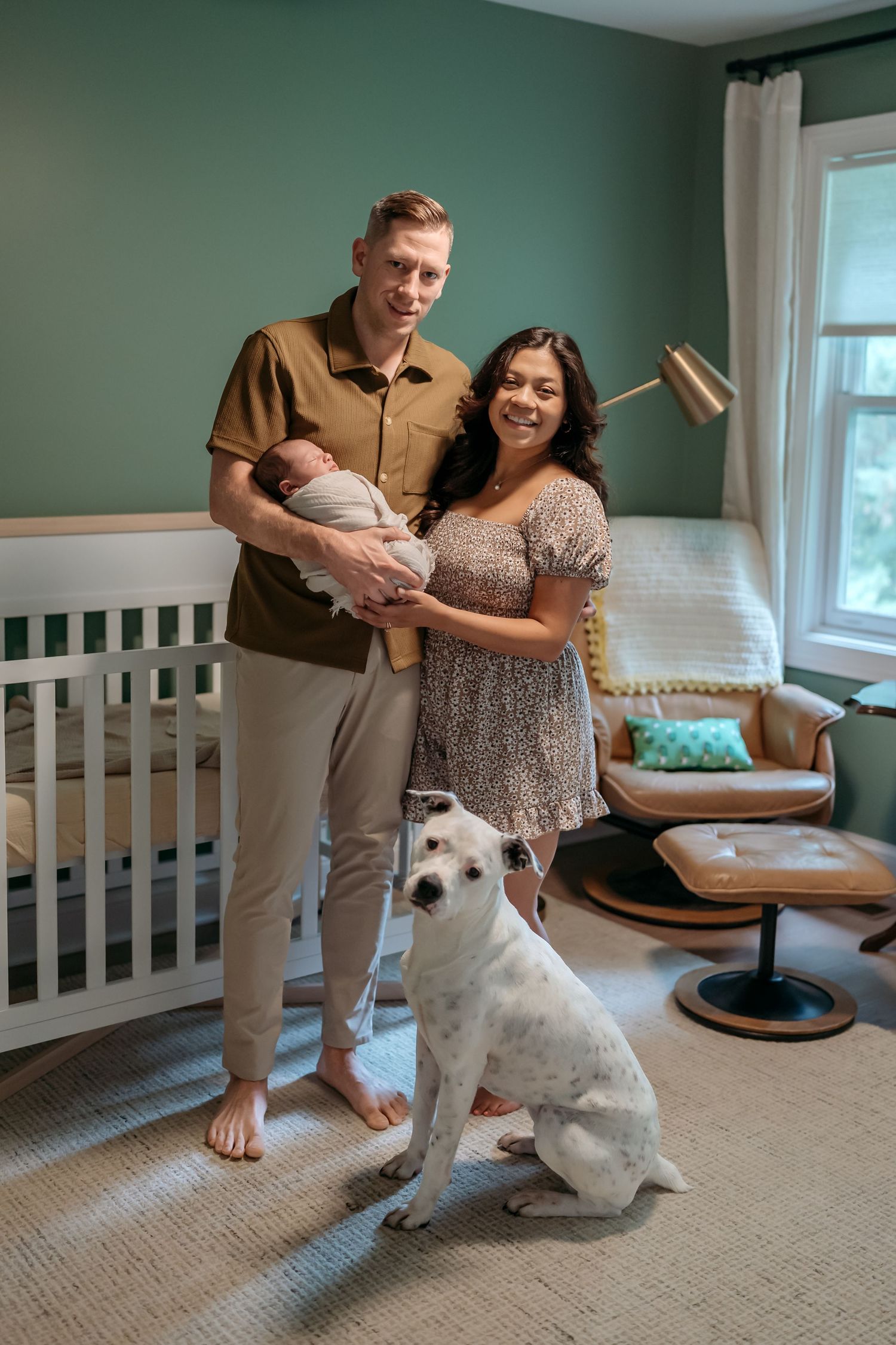 A couple practices dance steps together in a living room with their white dog watching from the corner.