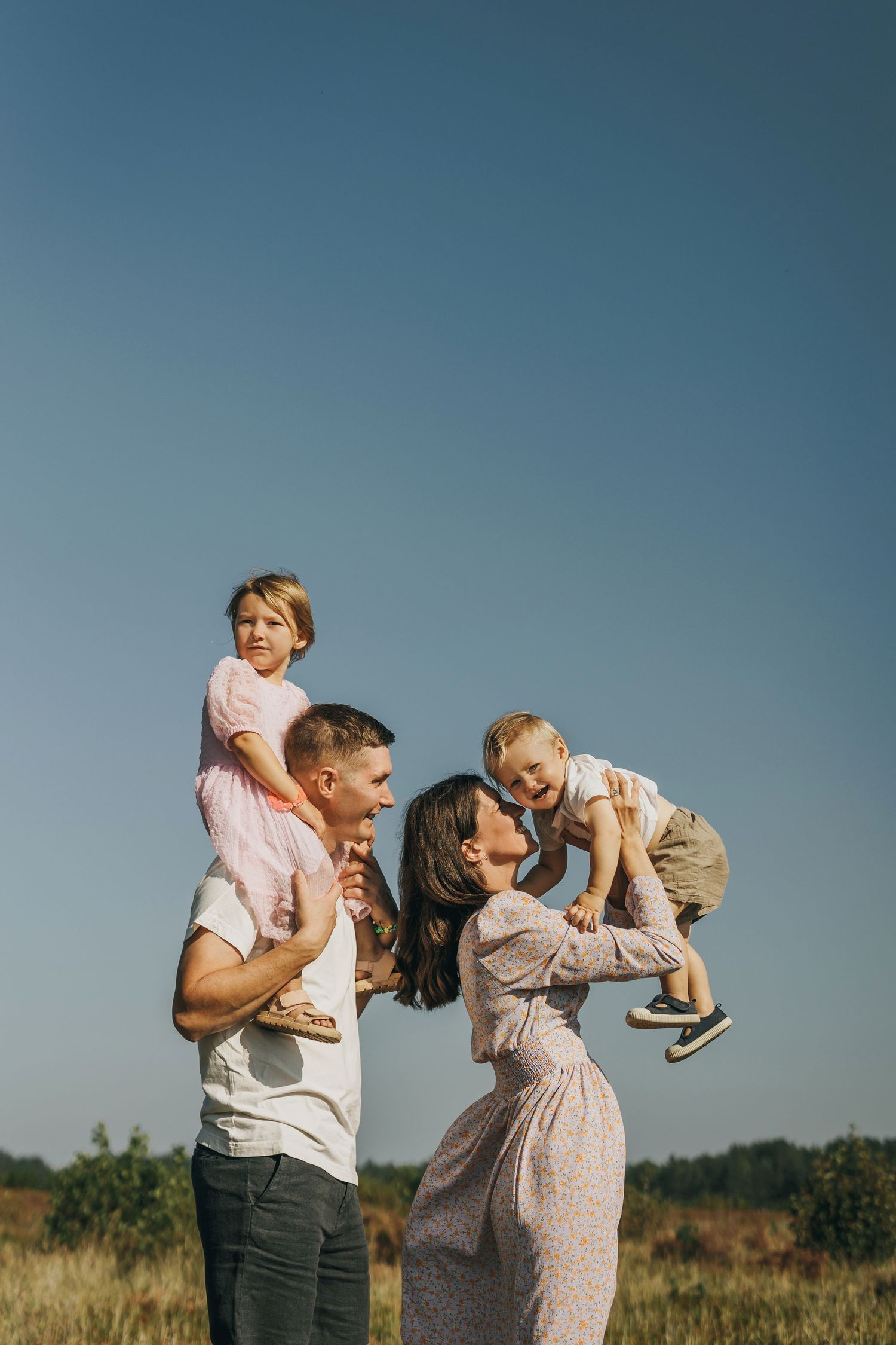 En pappa som har sin dotter på axlarna och en mamma som lyfter upp lillebror mot himlen i Söderhamn