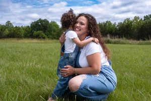 A tender embrace between parent and child in a sunny meadow.
