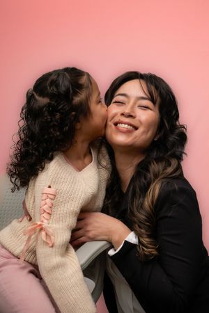 Two people share a tender moment against a pink background in a progressive sequence of intimate poses.