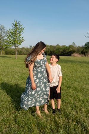 A touching moment between parent and child standing in a sunlit meadow.