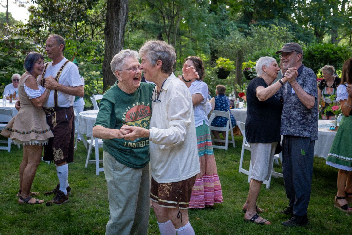 Couples dancing together at an outdoor summer gathering in a garden setting.