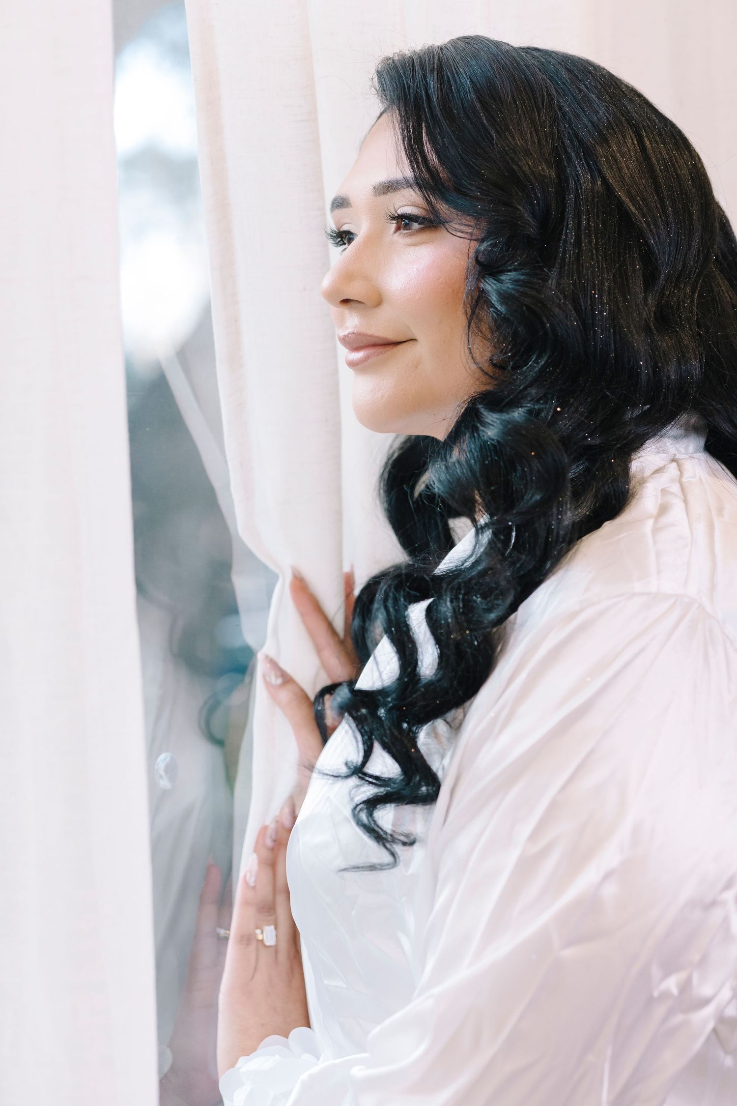 Hands with wedding rings embrace in an intimate moment against white lace dress fabric.