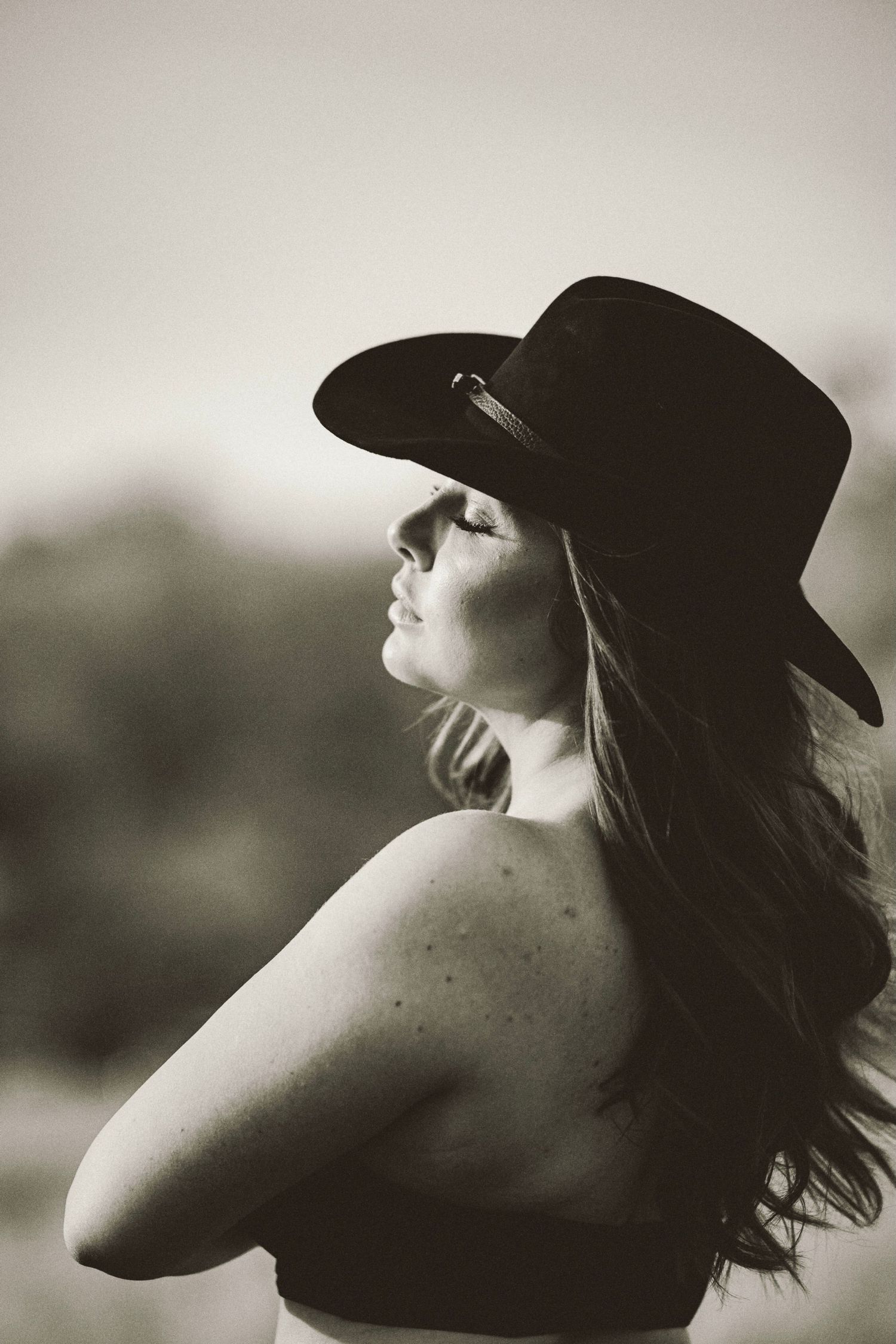 Cowgirl porträtt i svartvitt – kvinna i cowboyhatt och bustier med intensiv blick | Porträttfotograf Malmö