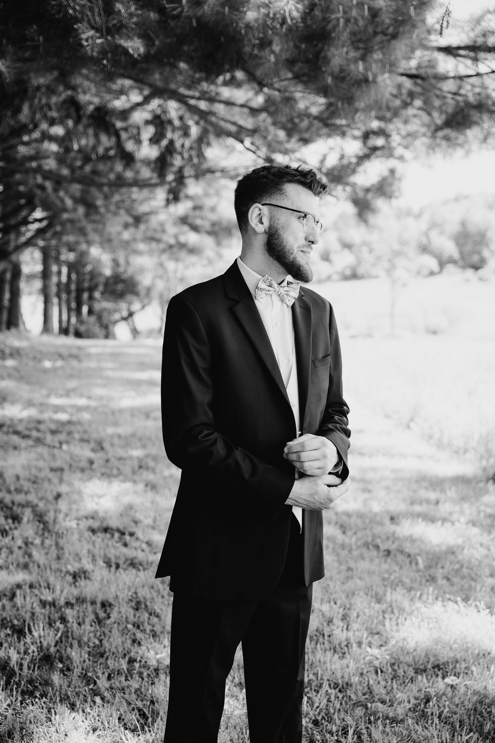 Black and white portrait sequence showing person in formal suit jacket looking thoughtful in outdoor natural setting.