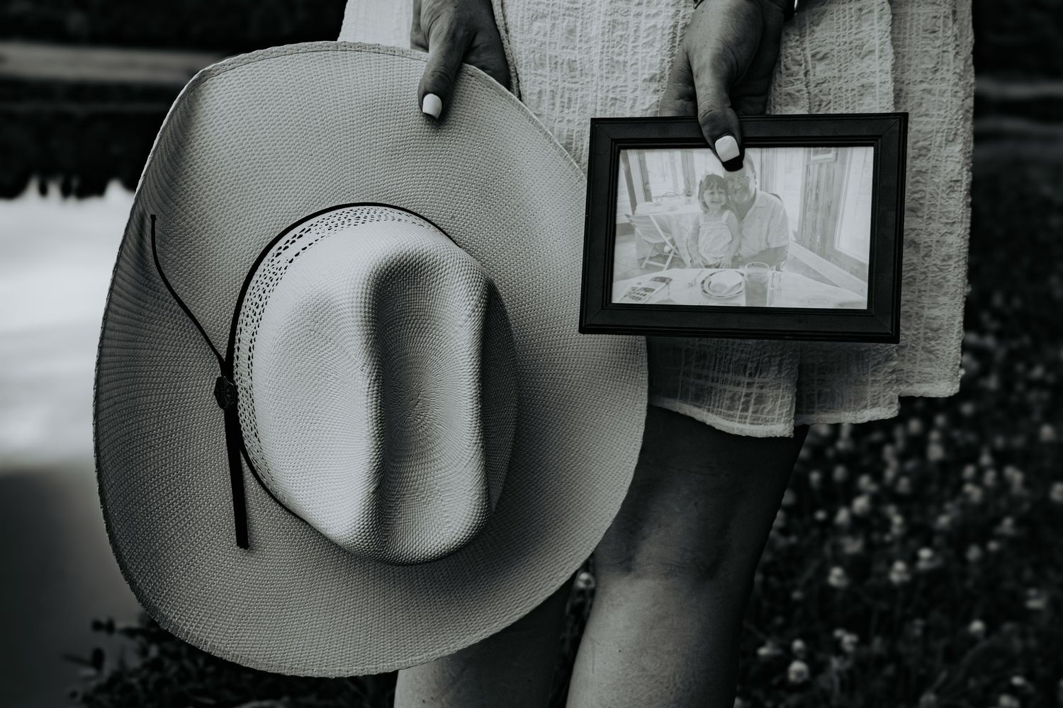 A row of western-style cowboy hats hanging on a wall display with wooden hooks and framed artwork in the background.