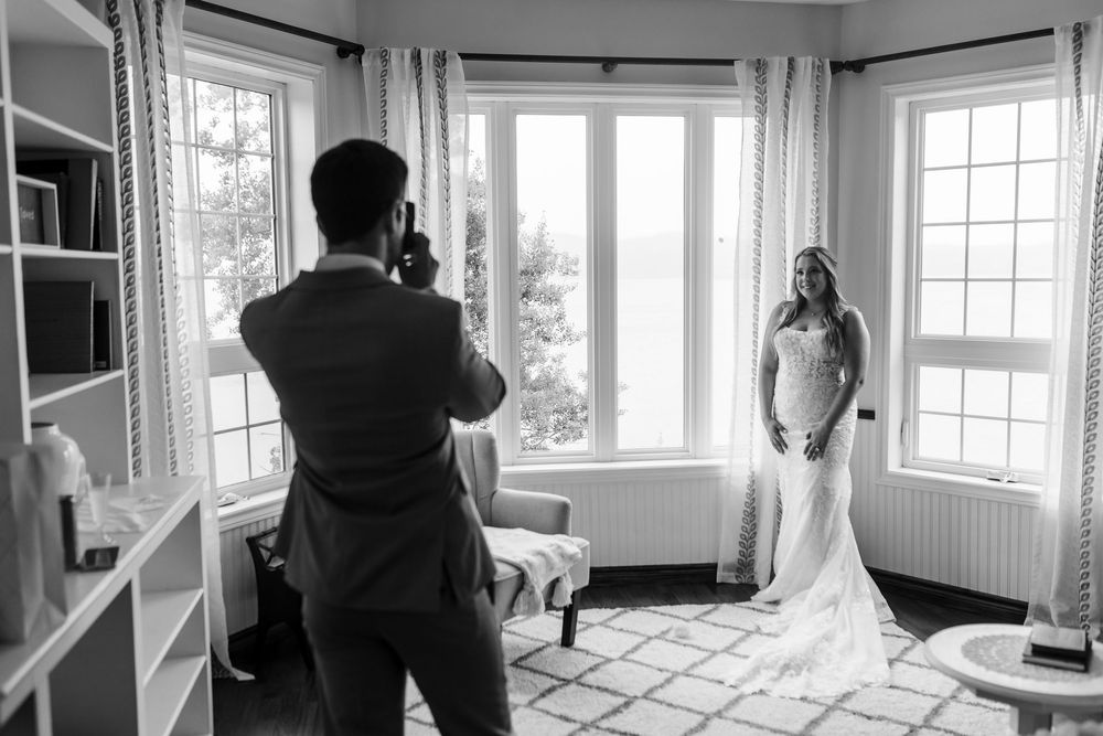 Panoramic black and white view of a bright sunlit room with large windows and people scattered throughout.