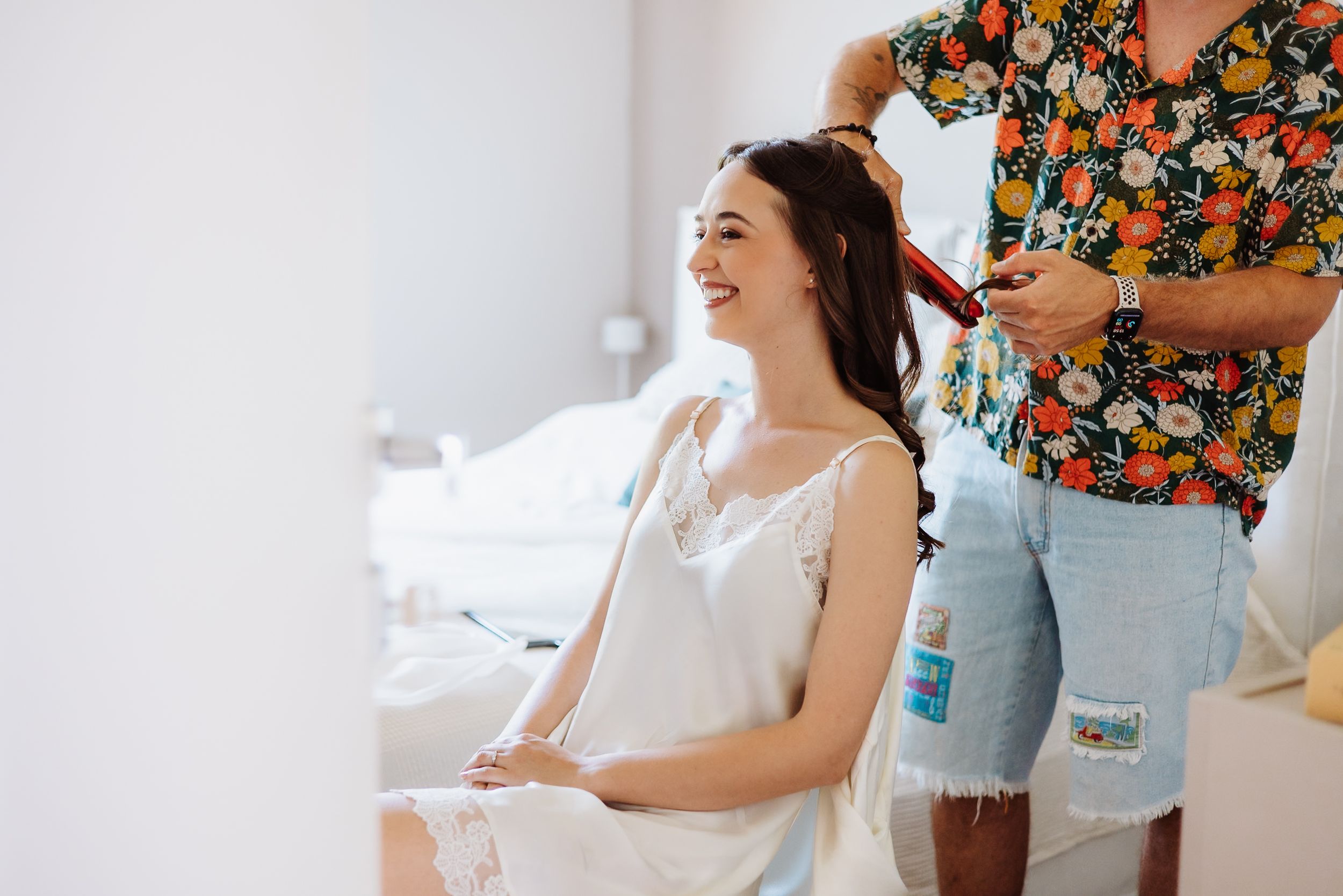 Woman in floral robe getting ready for special occasion with smiling bridesmaids in matching robes.