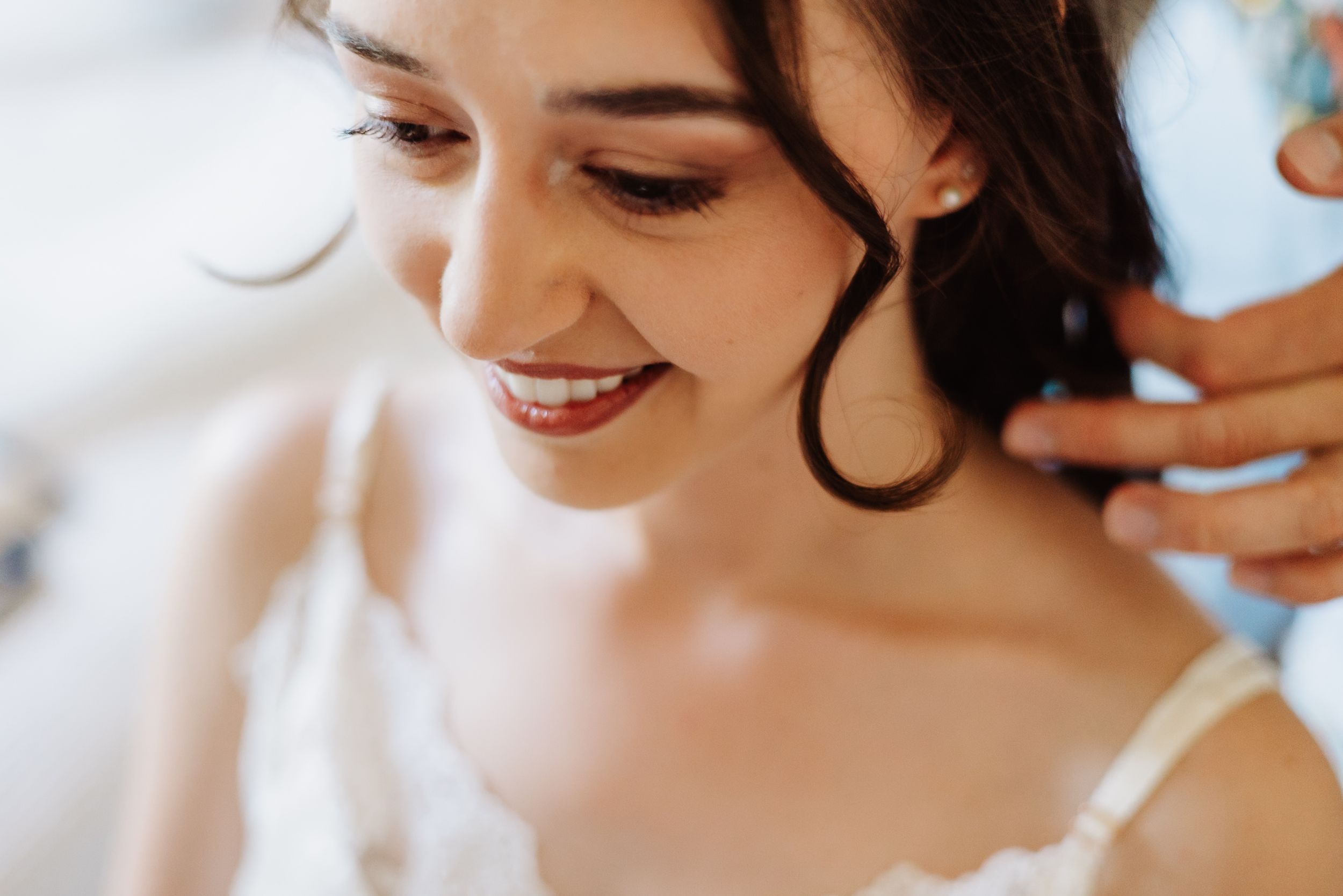 A smiling person with dark curly hair is captured in a candid close-up party moment.