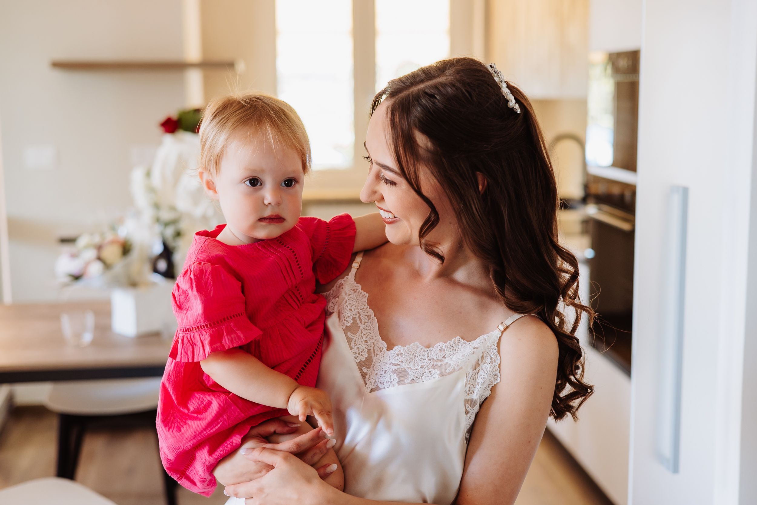 Natural light photography sequence shows joyful candid moments between parent and child in a bright kitchen interior.