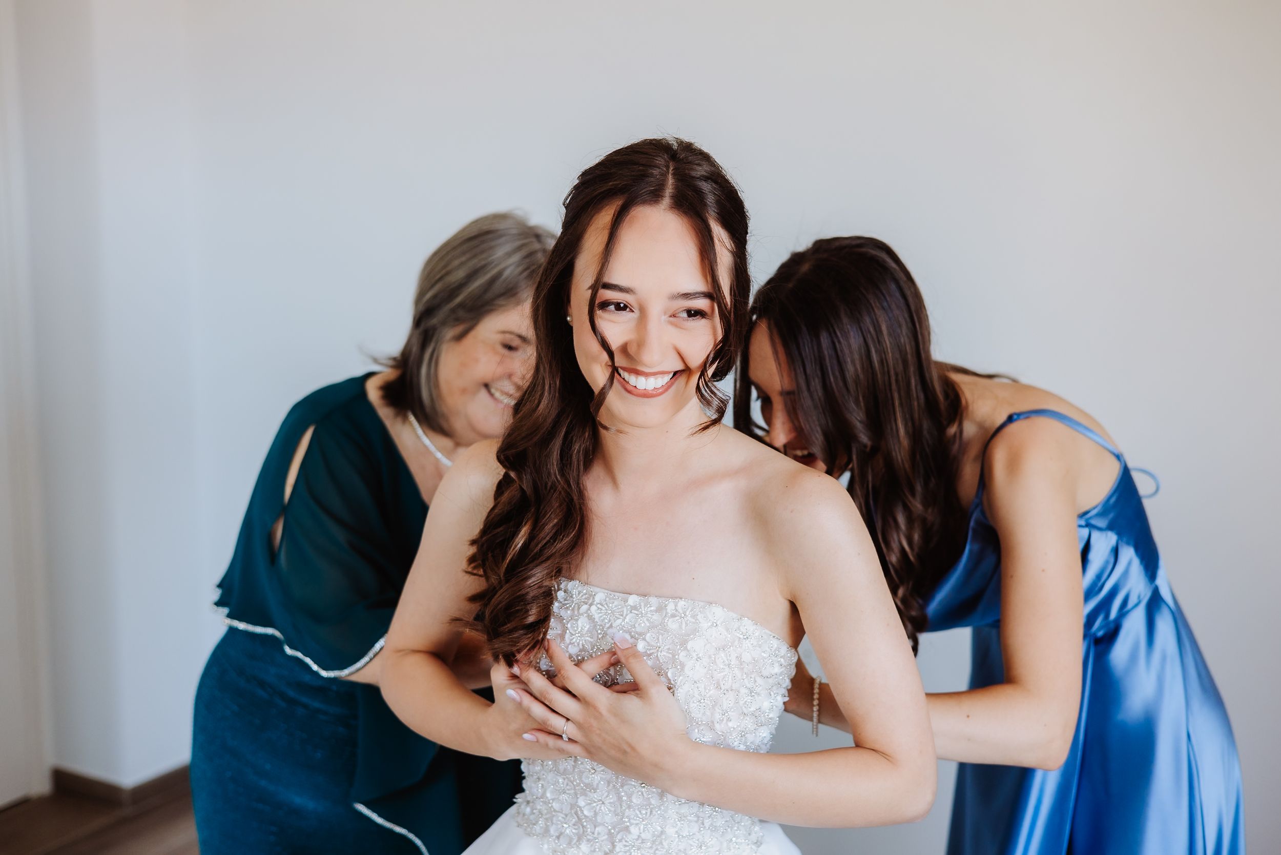 A bride and bridesmaids in blue dresses share joyful moments in a series of candid getting ready photos.