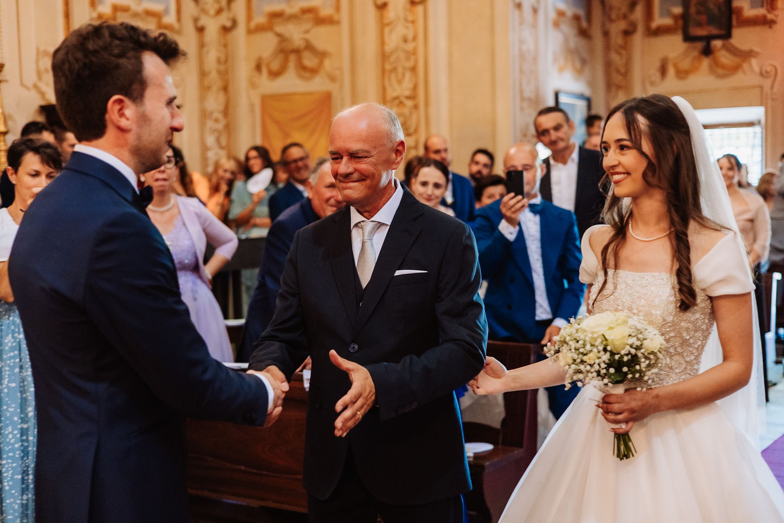 A wedding reception scene shows guests gathered in an elegant room with ornate golden decor.