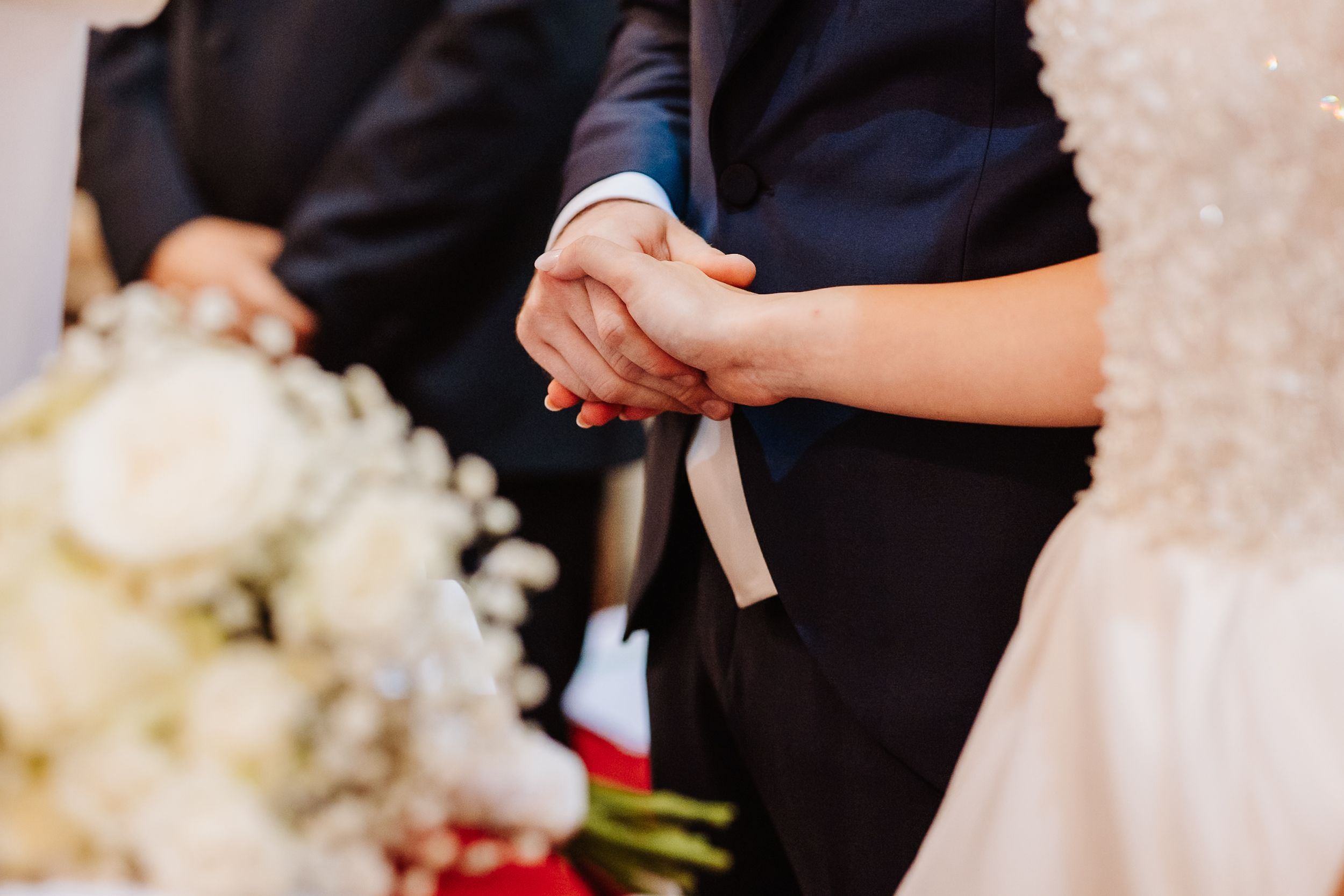A traditional wedding ceremony moment captured during a ring exchange by figures dressed in formal black and white attire.