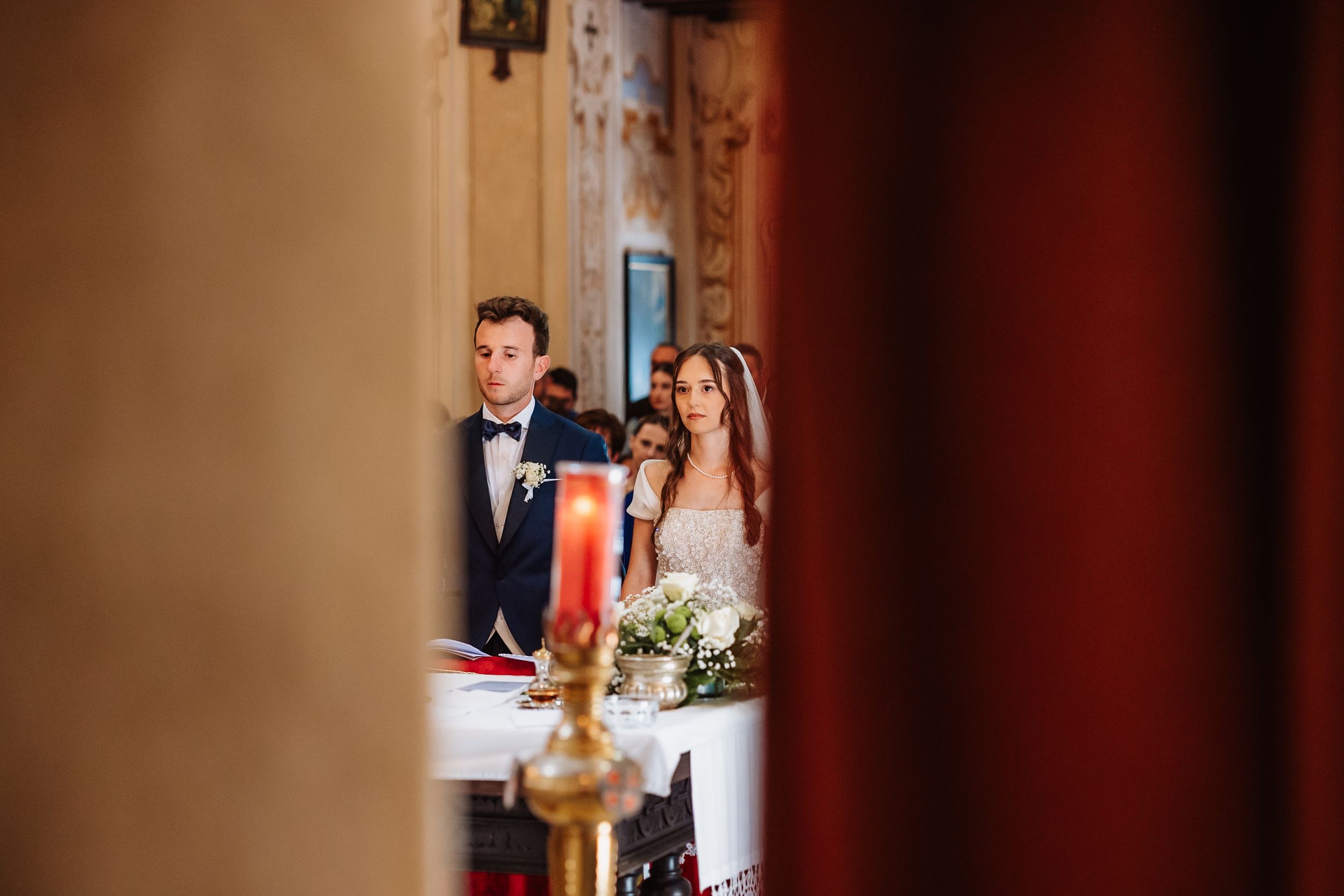 People stand in formal attire for a wedding ceremony in a beautifully decorated venue setting.